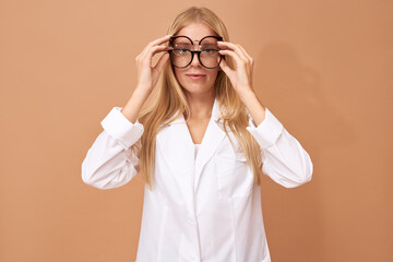 Eyesight, vision and optics concept. Studio image of young blonde Caucasian female ophthalmologist...