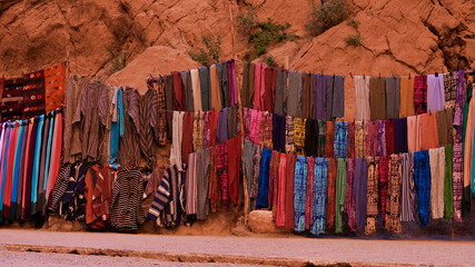Colorful traditional Berber clothes and carpets offered for sale in famous Todgha Gorge near...
