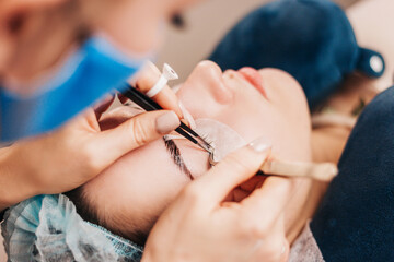 Obraz na płótnie Canvas Girl extends eyelashes in a beauty salon - preparing for a date