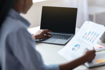 Black Female Employee Using Laptop With Black Screen And Working With Documents