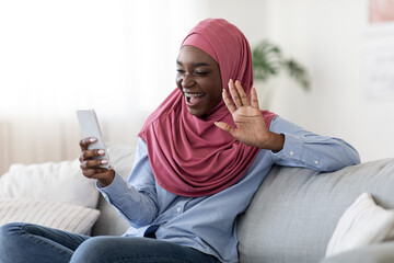 Cheerful Black Islamic Lady Making Video Call Via Mobile Phone At Home