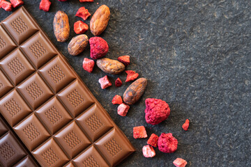 Chocolate bars handmade with strawberries and pistachios on a black background. Craft vegan...