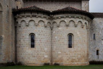 The front view on symmetrical architectural element on the abbey  Rounded walls of an apse with arch windows from limestone.