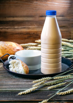 Baked milk in a cup and bottle on iron tray with peace of bread 