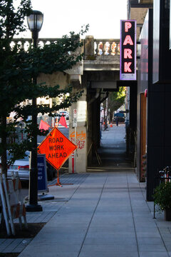 Road work sign near a bridge and a parking garage