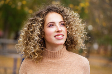 Hairstyle curly hair, portrait of a young blonde girl in an autumn park
