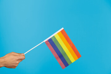 Hand with LGTB flag on blue background. Symbol lgtb