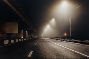 Fototapeta na wymiar Foggy misty night road illuminated by street lights
