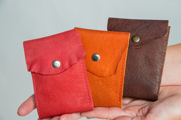 Group colorful Wallet of Leather skin on white background.Three Fashionable modern leather pouch wallets in hand, close up, brass snaps, bright colors.Trend accessories.