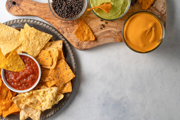 Mexican corn tortilla chips and wooden board with sauces on white background. Appetizing food. View from above. Flat lay. Space for text.