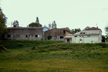 Abandoned hangars. Industrial building  surrounded by the vegetation. Houses with broken windows.