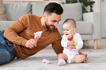 Happy Father Playing With Baby Holding Toys In Living Room