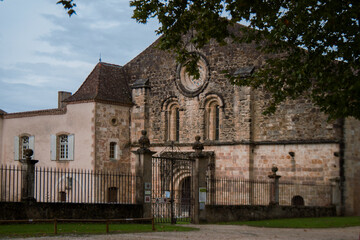 A view of an abbey. Facade with arch windows. Black fence along the historical building. Calm autumn day over the blue sky. Old stone architecture.