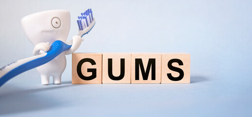 The inscription GUMS on wooden cubes on a light blue background together with pedmets related to...