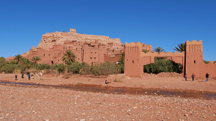 Tourists shooting pictures with a camel below historic Moorish ksar Ait Benhaddou, UNESCO World...