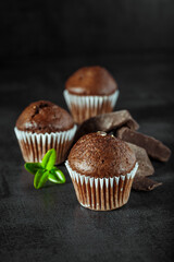 Chocolate cupcake with icing and chocolate bar in Dark lighting,Homemade delicious chocolate muffin on wooden background close-up