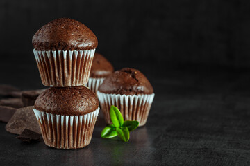 Chocolate cupcake with icing and chocolate bar in Dark lighting,Homemade delicious chocolate muffin on wooden background close-up