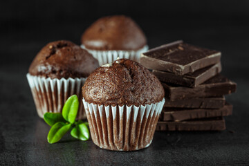 Chocolate cupcake with icing and chocolate bar in Dark lighting,Homemade delicious chocolate muffin on wooden background close-up