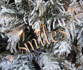 Word Smiles wooden cutout decoration on white Christmas tree