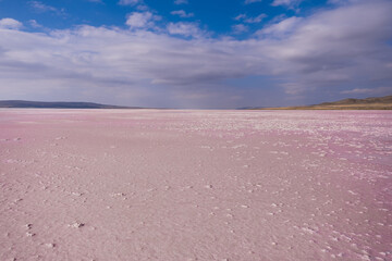 Drained salt lake with blue and cloudy sky. The salt lake turned pink due to algae in the water.