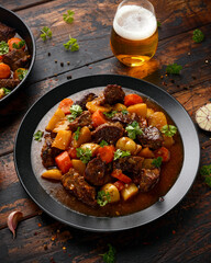Beef Stew with carrot and baby potato in black plate on wooden table