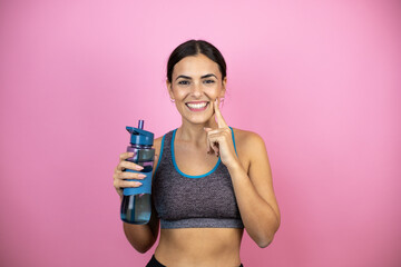Young beautiful woman wearing sportswear over isolated pink background smiling confident showing and pointing with fingers teeth and mouth