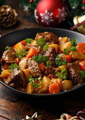 Christmas Beef Stew with decoration, gifts, green tree branch on wooden rustic table