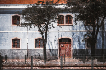 Frontal view of a beautiful antique house facade in a bluish color of plaster, with old flaked...