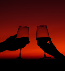 two hands toasting wine glasses at the sunset. celebrate, make a toast.
