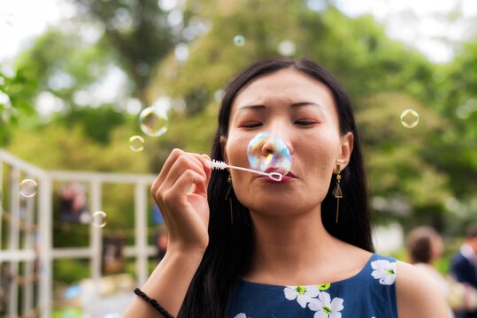 Chinese woman blowing bubbles outside on a summer day