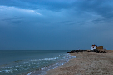 Small white house on the bank of a sand spit in cloudy weather