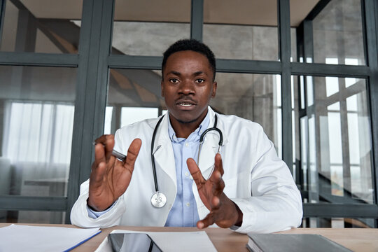 Black Male Doctor Talking To Web Cam Consulting Patient Via Virtual Telemedicine Advice. African Physician Making Online Telehealth Video Call For Remote Appointment Tele Health Care Chat. Webcam View
