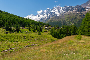 Little Triftalp village with the preserved old wooden farmhouses and majestic Mischabel massif and Dom peak behind