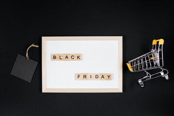 Black Friday sale. Mini shopping cart in frame on black background.