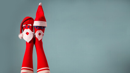 Cute christmas legs. Funny woman legs wearing socks with faces and santa claus hats. Xmas party,...