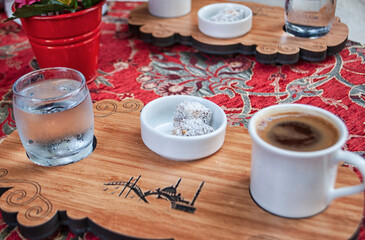 Turkish delight with a cup of turkish coffee and a glass of water on the wooden board.