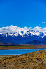 Fototapeta na wymiar Snow covered mountains and green valleys with a lake in New Zealand