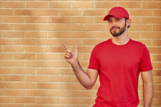 Young cheerful caucasian male courier in red uniform