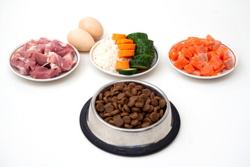 Dry pet dog food in bowl with natural ingredients. Raw meat, fish, vegetables, eggs and salad....