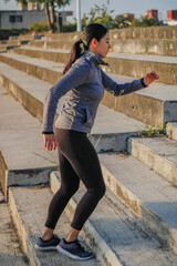 Latin Hispanic woman with black hair doing yoga exercise outdoors in a park