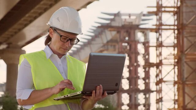 Woman foreman working on construction site using laptop computer.