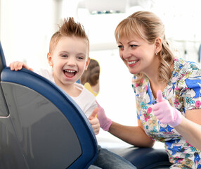 Moscow, Russia - 18 March, 2019: Kid boy and his dentist show us thumbs up after dental check on background with dental office 