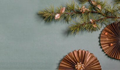 Golden-black paper fan and Cristmas tree branch on the green background. Flat lay photo, top view. Space for text invitation or greeting.