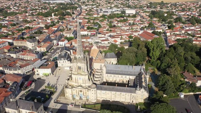 View from drone of houses and ancient Roman Catholic Cathedral of Lucon town at summer day, France