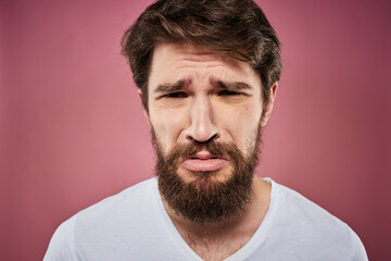 Obraz premium Emotional bearded man in white T-shirt discontent pink background