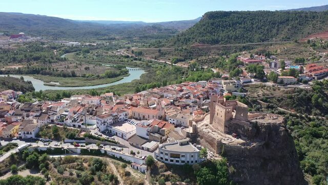 Picturesque autumn landscape with small Spanish town of Cofrentes located in mountainous area of Valencia province overlooking ancient fortified castle
