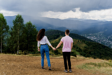 Obraz na płótnie Canvas Couple looking at the mountain hills before raining. Feeling freedom together in Karpathian mountains. Tourism travelling in Ukraine.