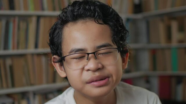 Portrait of young Asian student boy tired sleepy and yawning when reading a book, student tired when studying hard
