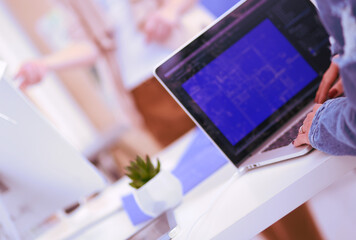 Two young woman sitting near desk with instruments, plan and laptop.