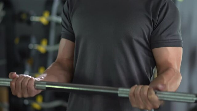 Unrecognizable Asian young man lifting up a barbell for bicep and body exercise